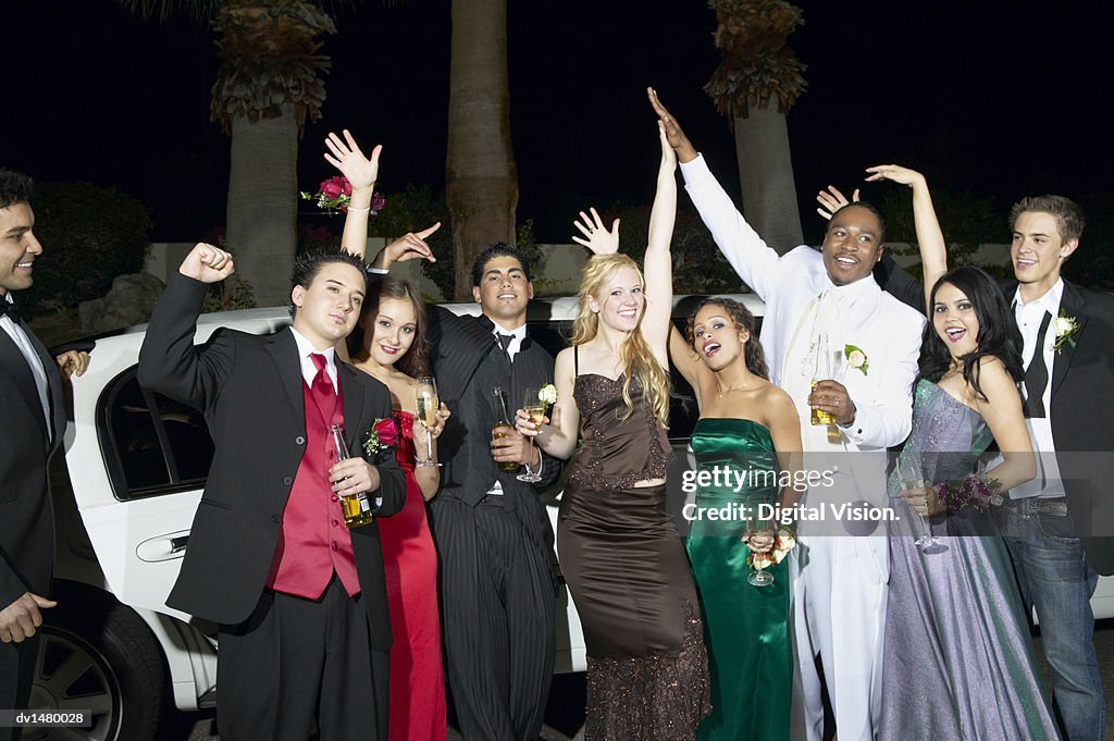 Teenage Boys and Girls Standing in Front of a Limousine Dressed for Their High School Prom