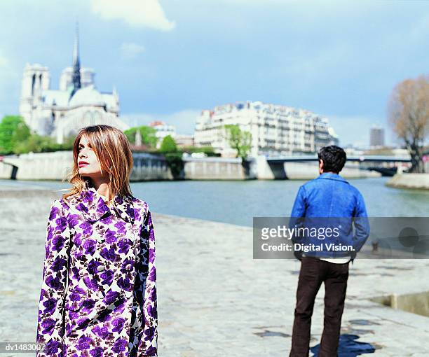 young couple stand on the left bank of the river seine with notre dame in the background - left behind ストックフォトと画像