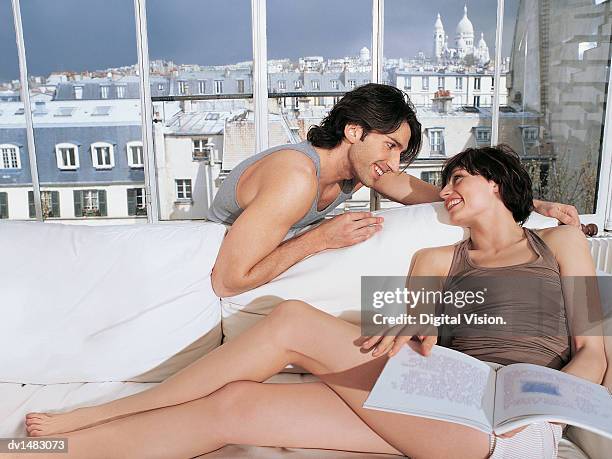 couple sitting face to face on sofa of luxury apartment with views over paris, sacre coeur - coeur stock pictures, royalty-free photos & images