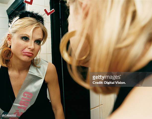 young, sad woman wearing a deely bopper and a sash looking into a mirror in the women's room - 女性用トイレ ストックフォトと画像