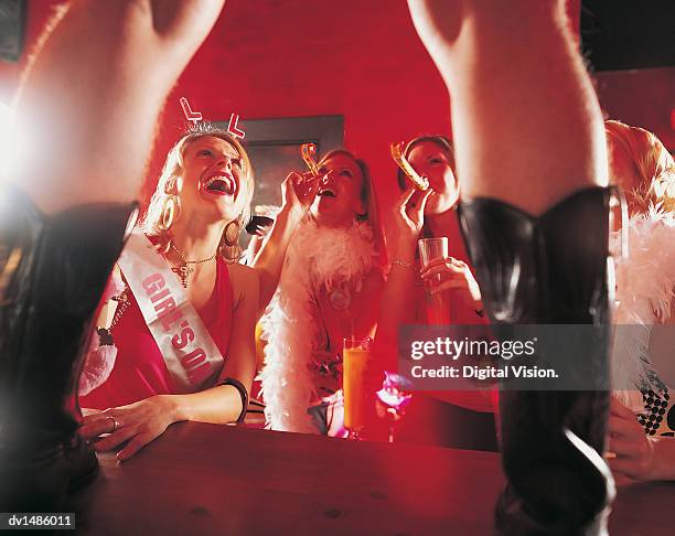 woman looking at a male stripper standing on a bar counter at a hen night - haarreifen mit sternchen stock-fotos und bilder