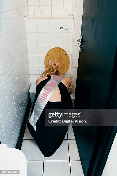 rear view of a young woman vomiting and crouching in front of a lavatory - party peinlich stock-fotos und bilder