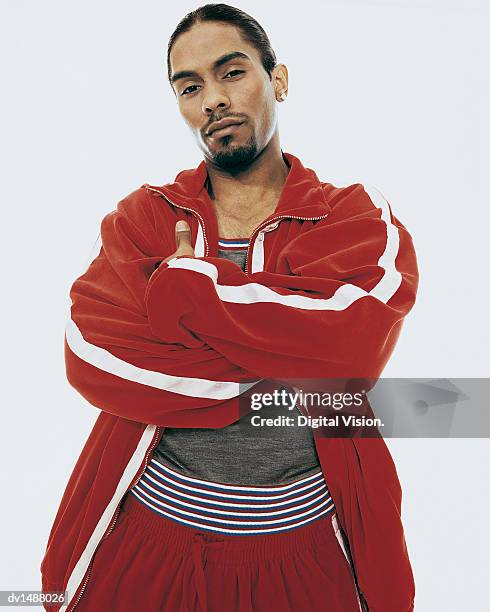 young man wearing a tracksuit with his arms crossed - chándal fotografías e imágenes de stock