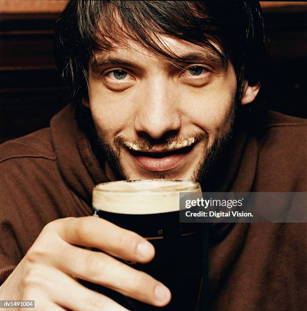 young man enjoying a drink of stout in a pub - stoutöl bildbanksfoton och bilder