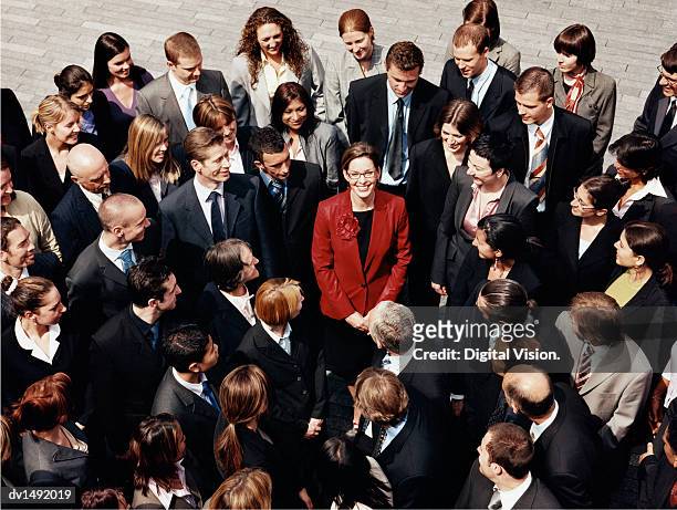 businesswoman standing outdoors surrounded by a large group of business people - omgeven stockfoto's en -beelden