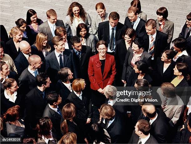 businesswoman standing outdoors surrounded by a large group of business people - surrounding stock pictures, royalty-free photos & images