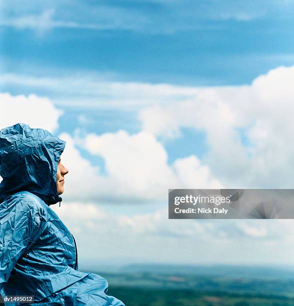 man wearing a hooded cagoule sitting out in the countryside - kagoul stock pictures, royalty-free photos & images