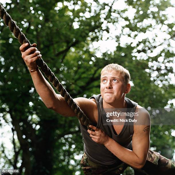 man climbing a rope on an assault course - army obstacle course stock pictures, royalty-free photos & images