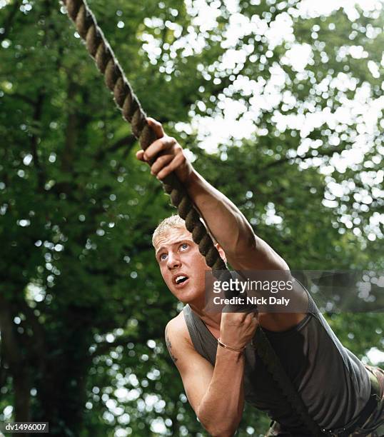 man climbing a rope on an assault course - obstacle course stock pictures, royalty-free photos & images