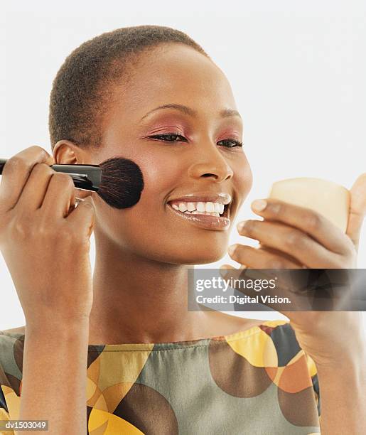 woman applying blusher as she looks in a hand mirror - woman applying blush stock pictures, royalty-free photos & images
