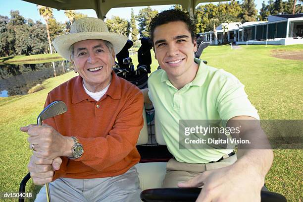 portrait of a senior man and his mature son sitting in a golf buggy on a putting green - putting clothes son stock pictures, royalty-free photos & images