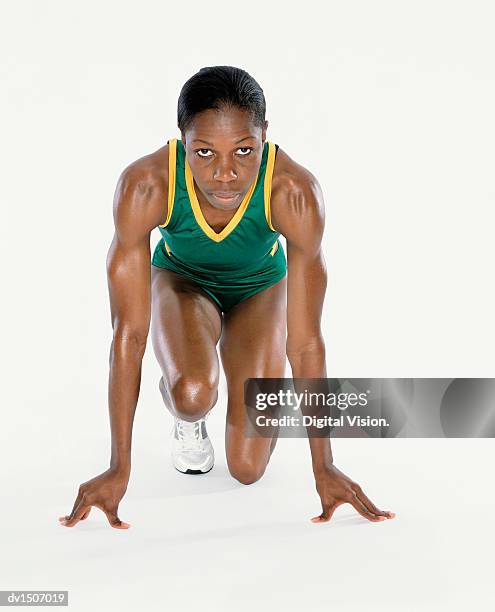 front view portrait of a female athlete crouching down wearing sports shorts and a vest - running shorts foto e immagini stock