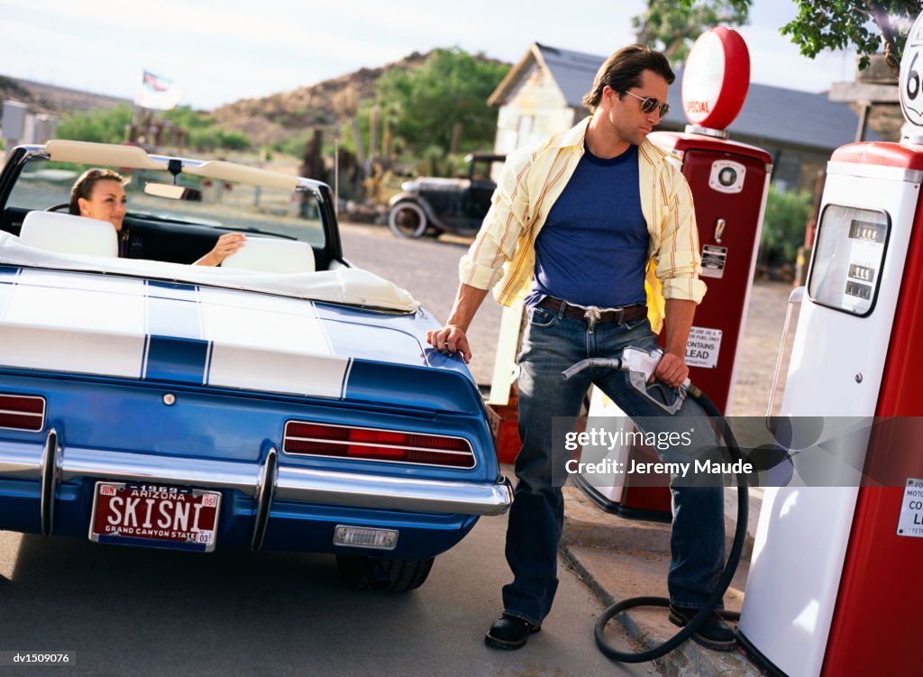 Man and a Woman Refuelling a Classic Convertible in a Petrol Station