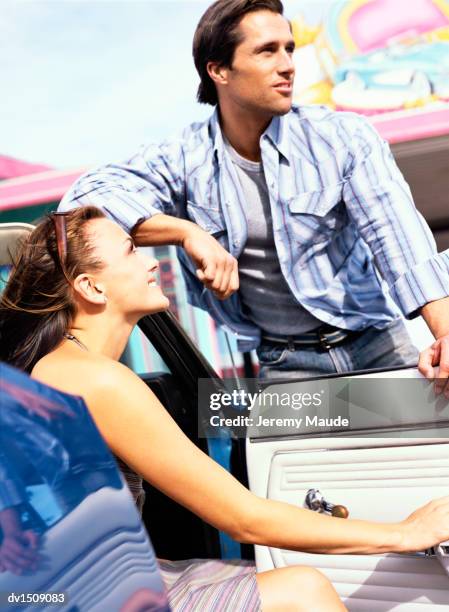 young couple leaning on an open car door - leather door stock pictures, royalty-free photos & images
