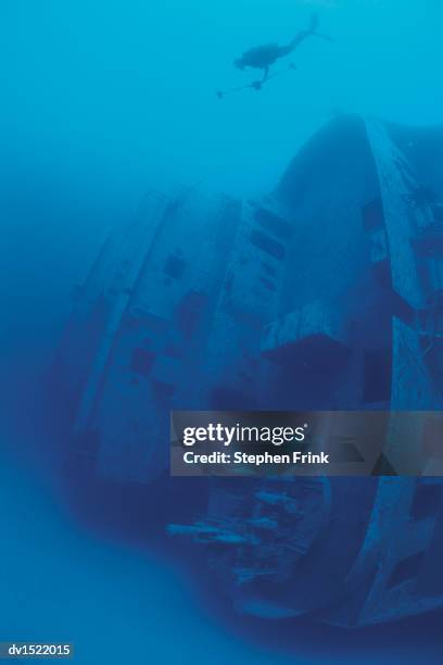 scuba diver moving towards shipwreck on seabed, bermuda - islas del atlántico fotografías e imágenes de stock