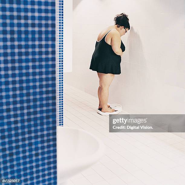 overweight woman standing on scales in a changing room - 女性用トイレ ストックフォトと画像