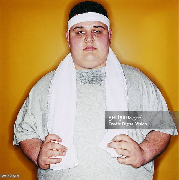 portrait of an overweight young man with a towel and wearing a sweatband - sweat band stock pictures, royalty-free photos & images