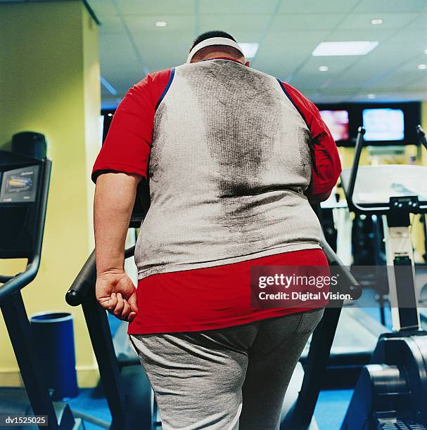 rear view of a fat man walking on an exercise machine in a gym - guy in sweatpants fat stock pictures, royalty-free photos & images
