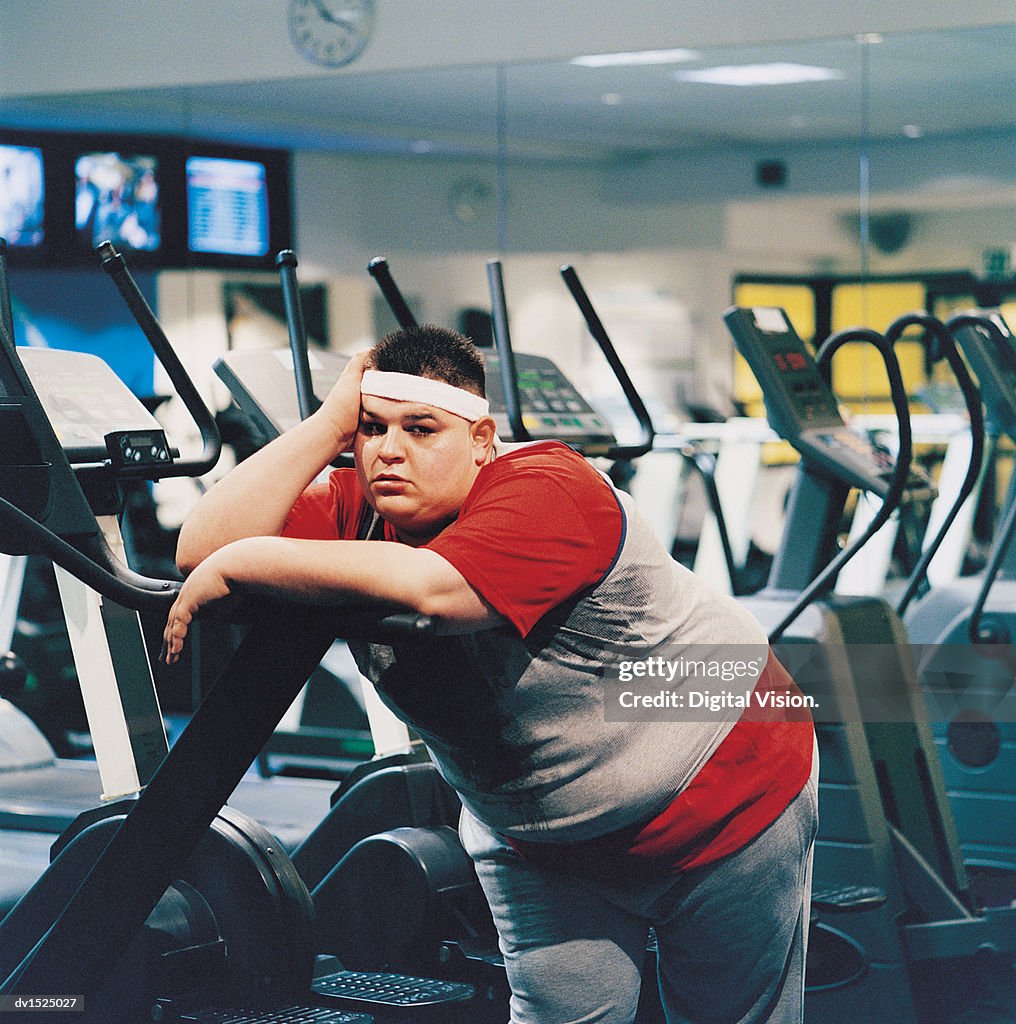 Fat Man Leaning Against a Running Machine