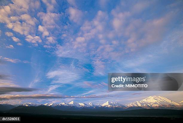 cloudy sky over a snow covered mountain range with mt mckinley in the background, denali national park, alaska, usa - cathedral peaks stockfoto's en -beelden