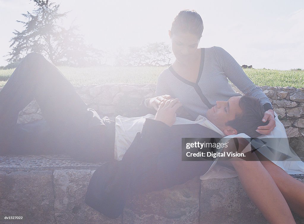 Man Lying on a Stone Wall on a Romantic Woman's Lap