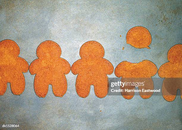 gingerbread men on a baking tray, one with its head broken off - figurita de jengibre fotografías e imágenes de stock