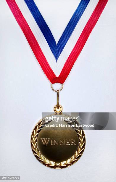 gold medal on a white background engraved with the single word winner - medaillen stock-fotos und bilder