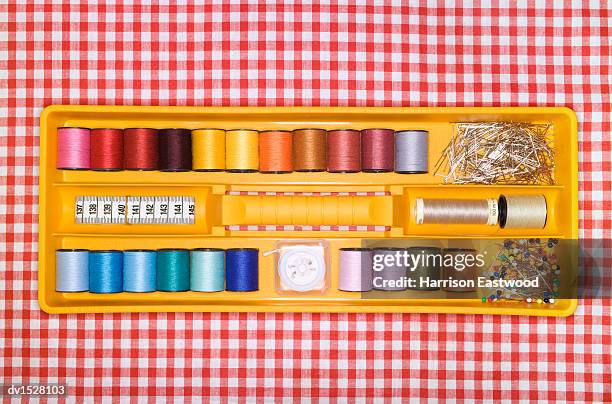sewing box filled with reels of thread, on a checked tablecloth - nadelbüchse stock-fotos und bilder