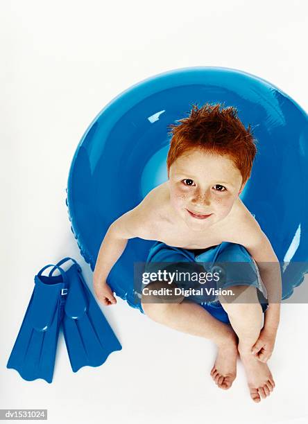 portrait of a young boy sitting on a rubber ring with flippers - rubber ring stock-fotos und bilder