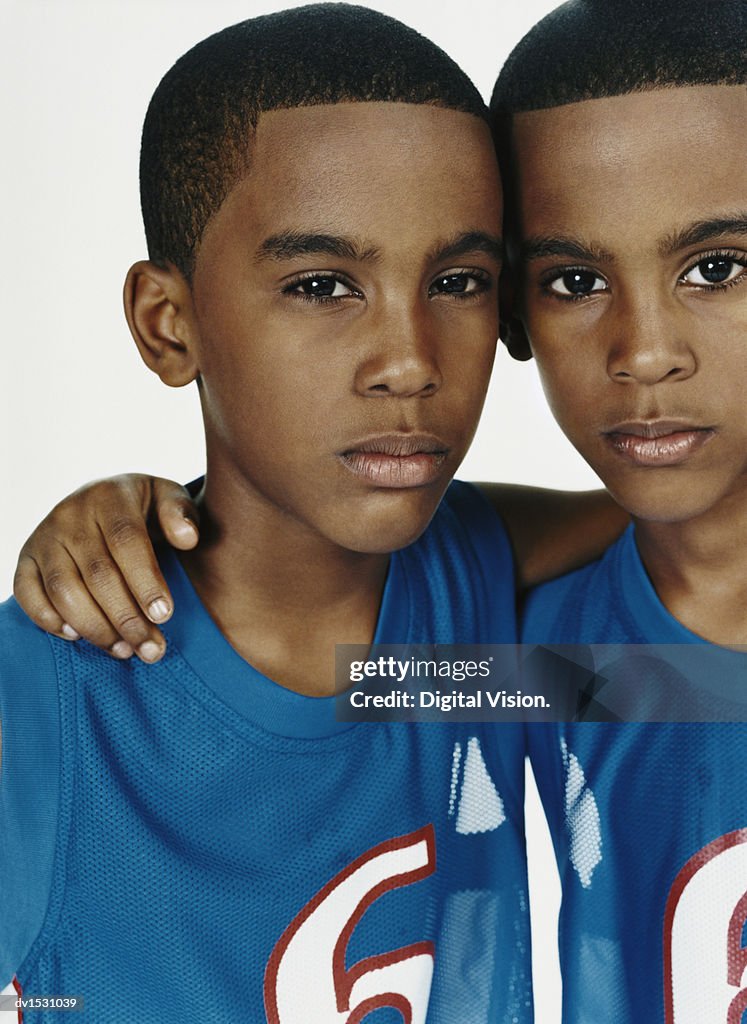 Studio Portrait of Twin Boys in Sports Strips Against a White Background