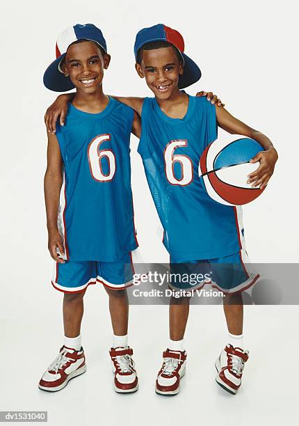 twinboys stand side-by-side in blue sports strips and holding a basketball - digital twin bildbanksfoton och bilder