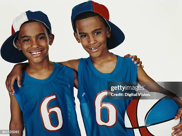 studio portrait of twin brothers in sports strips with arms around each other - digital twin stock pictures, royalty-free photos & images