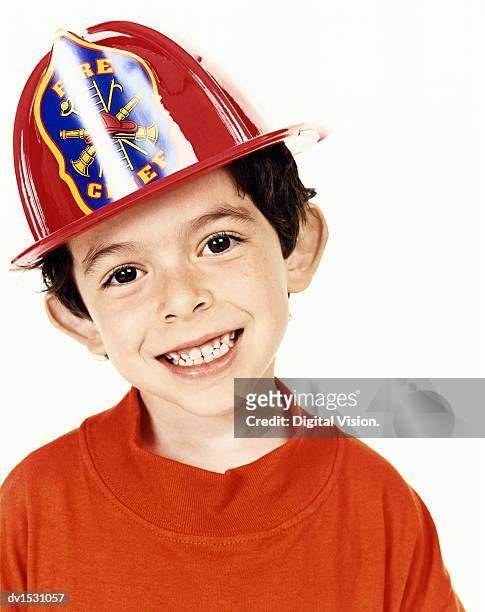 studio portrait of a young boy wearing a plastic fireman's helmet - boy fireman costume stock pictures, royalty-free photos & images
