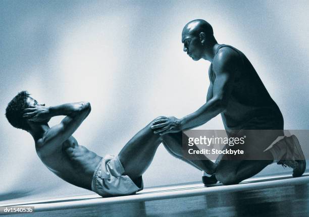 man performing sit-ups with second man holding legs - dv154053b foto e immagini stock