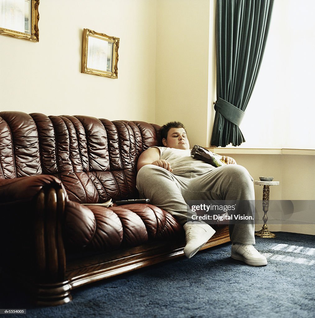 Young Man Lying On A Tv And Holding A Packet Of Crisps High-Res Stock Photo - Getty Images