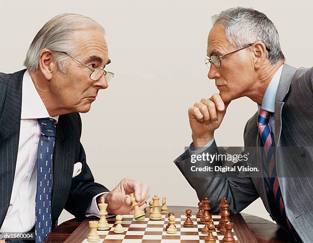 two businessmen looking face to face and playing chess - chess board businessman stock-fotos und bilder