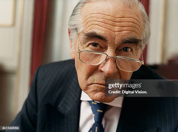 portrait of a sulking businessman wearing spectacles and a pinstripe suit - verärgert stock-fotos und bilder