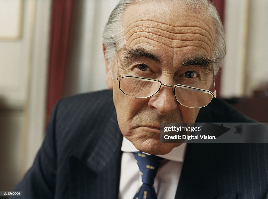 Portrait of a Sulking Businessman Wearing Spectacles and a Pinstripe Suit