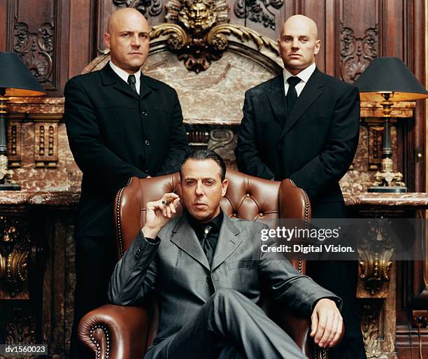 wealthy criminal sitting in an armchair between two bodyguards - ornate chair stock pictures, royalty-free photos & images