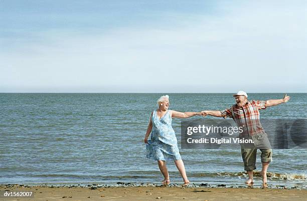 senior couple dancing at water's edge - couple de vieux drole photos et images de collection