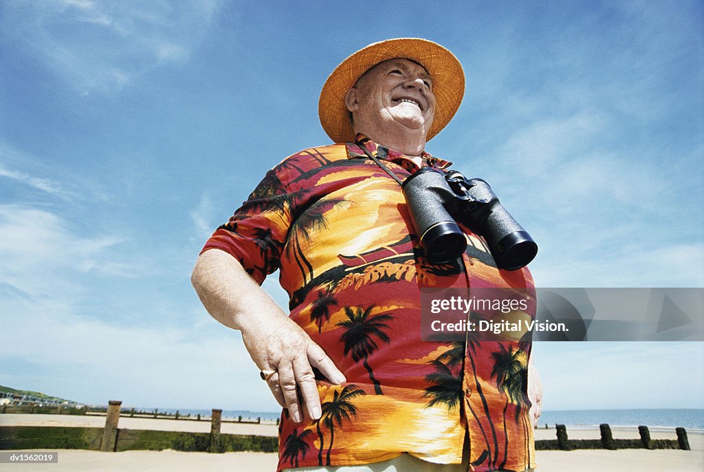 Low Angle View of A Smiling Senior Man Wearing a Hat and Binoculars