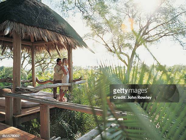 couple standing in a holiday home enjoying the view over the jungle, botswana, africa - jungle safari stock-fotos und bilder
