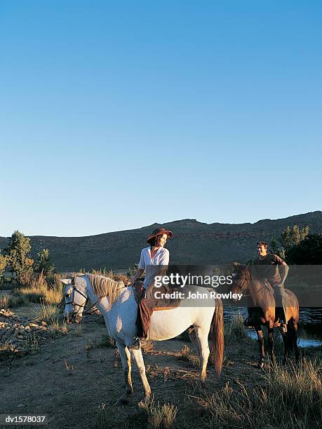 couple enjoying a ride on horses across scrubland in africa - bay horse 個照片及圖片檔