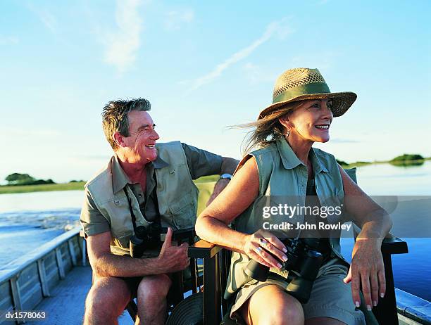 couple sitting on a boat on a river enjoying the view - südafrika safari stock-fotos und bilder