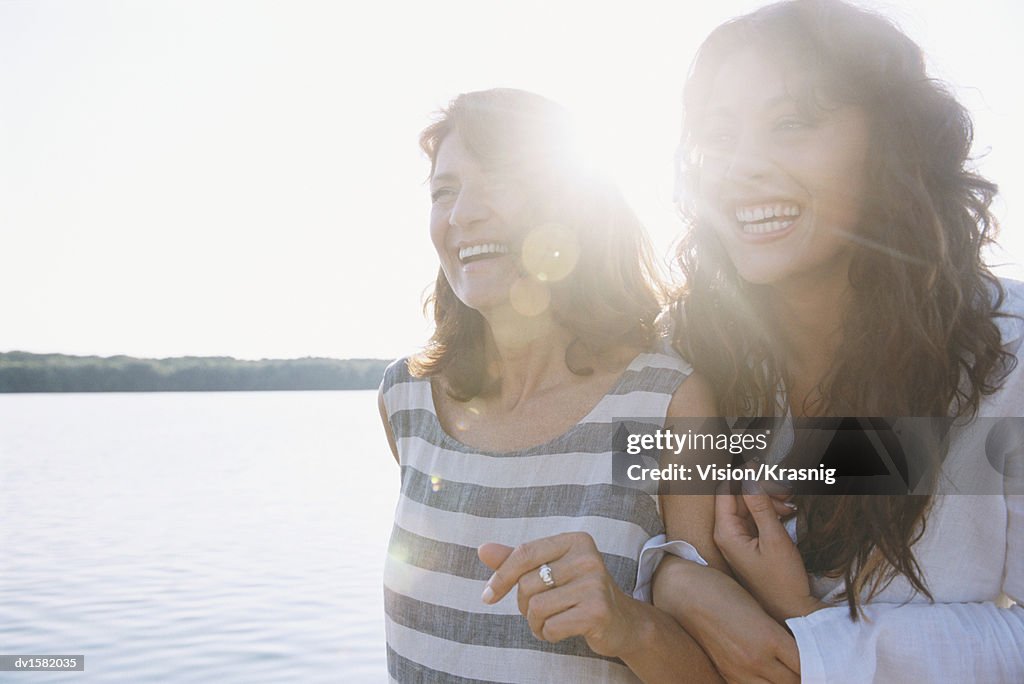 Mother and Daughter Standing Arm in Arm at Water's Edge Having Fun