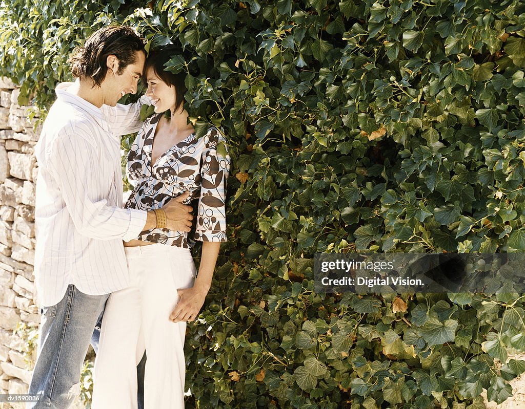 Young Couple Stand By a Stone Wall Embracing