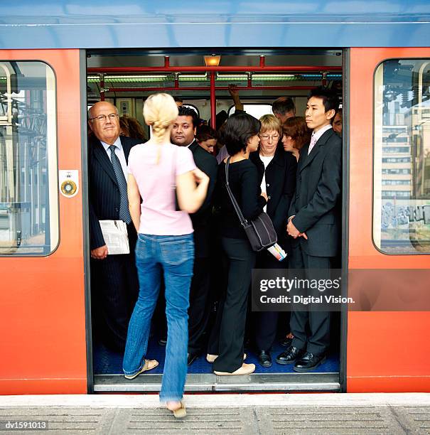 rear view of a blonde woman stepping onto a crowded commuter train - 通勤電車 ストックフォトと画像