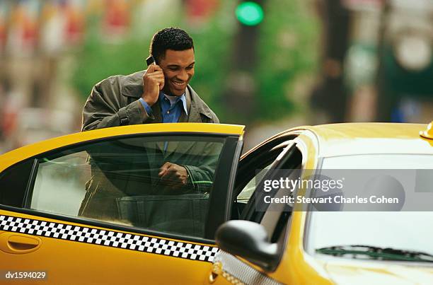 businessman using a mobile phone gets into a yellow taxi in new york - stewart stock pictures, royalty-free photos & images