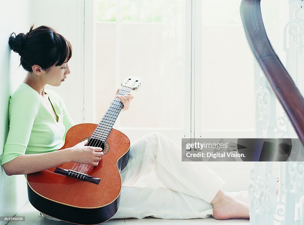 Woman Sits on the Floor Playing the Guitar, Domestic Interior