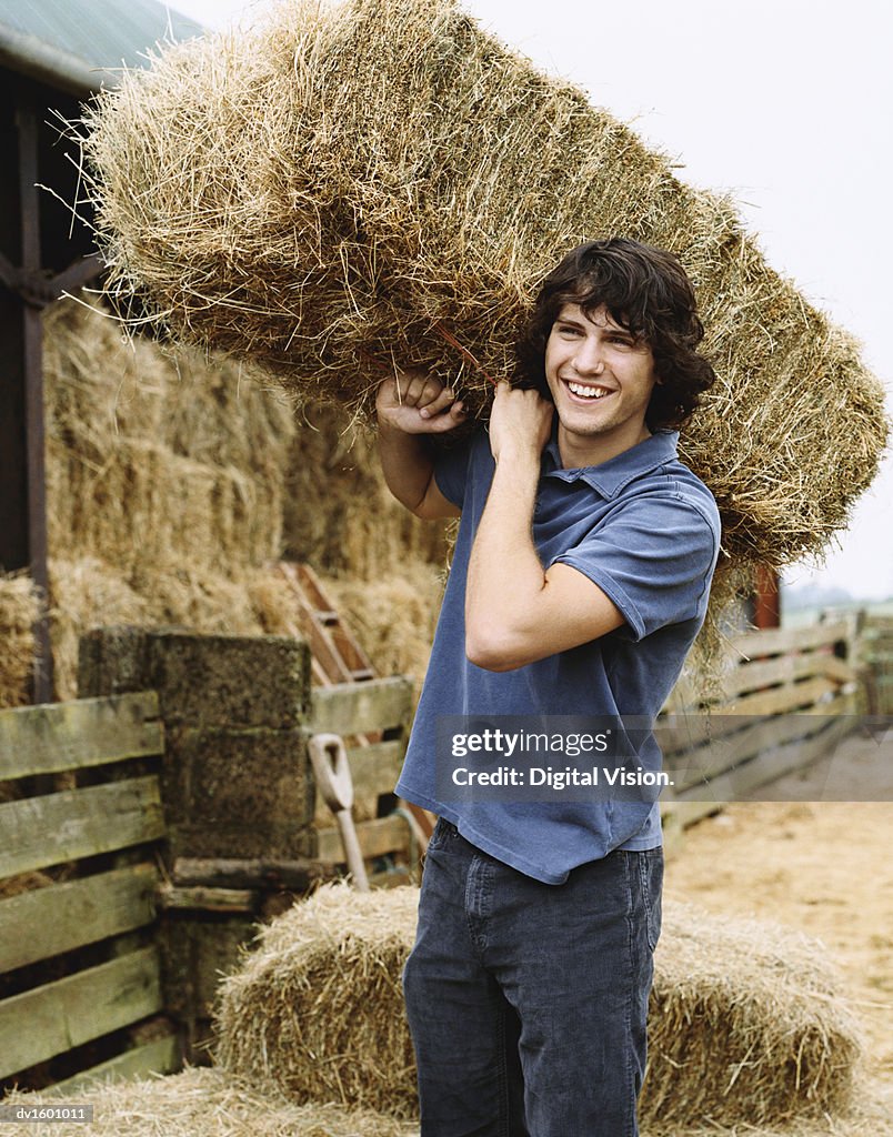 Young Farmer Carrying a Bale of Hay